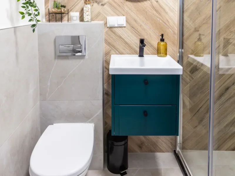 Blue wall hung bathroom unit with sink basin next to a small bathroom's toilet.