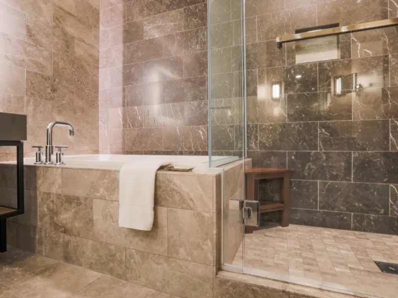 A luxurious fully tiled bathroom in a stone/marble effect.