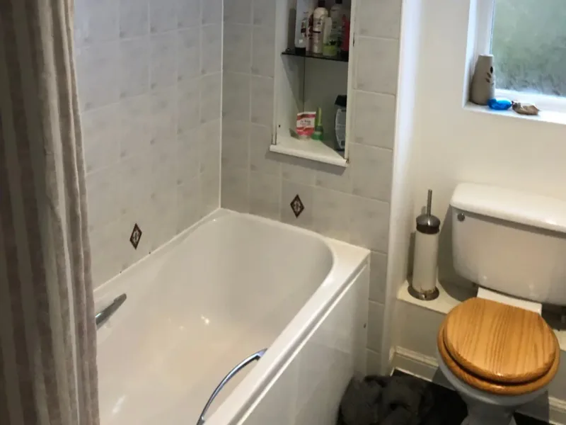 Old bathroom before renovation showing a tired and plain shower area.