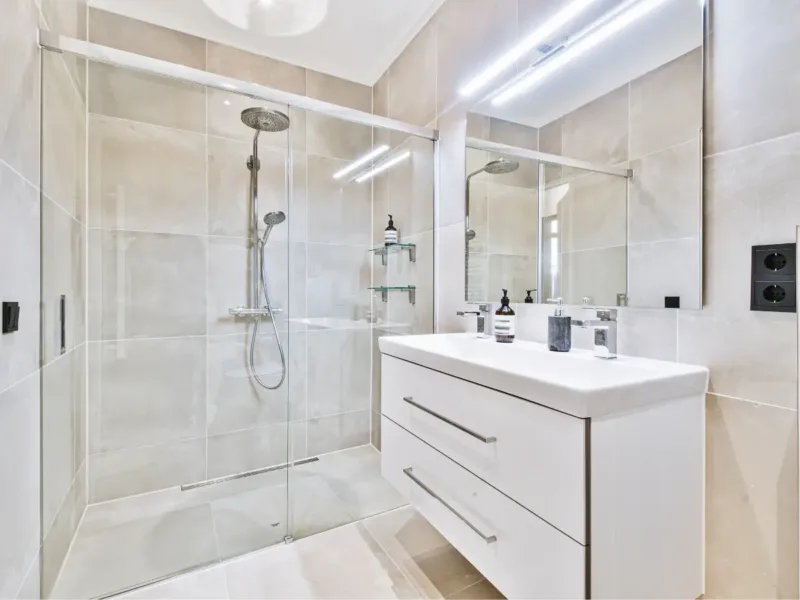 Modern and bright new bathroom with walk-in shower and sink unit.