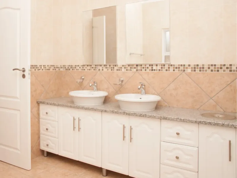 Long white and classic-styled bathroom modular units stretching across a bathroom wall.